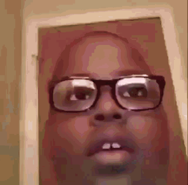 a close up of a person wearing glasses with a door in the background