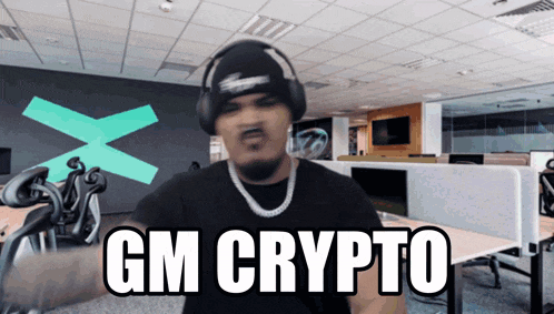 a man wearing headphones says " gm crypto " in an office