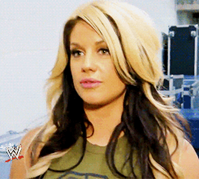 a woman with long blonde hair is wearing a t-shirt with a wrestling logo on her arm