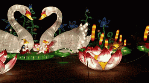 a couple of swans sitting on a leaf with flowers in the background