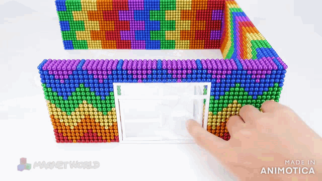 a person is playing with a rainbow colored magnet world game