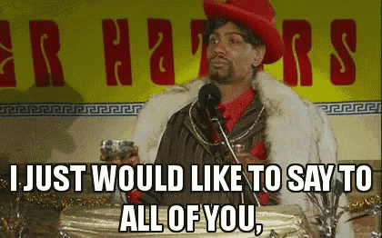 a man in a red hat and fur coat is giving a speech in front of a sign that says haters .