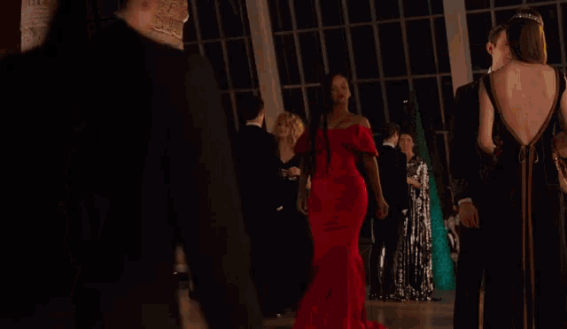 a woman in a red dress is standing in a room with other people