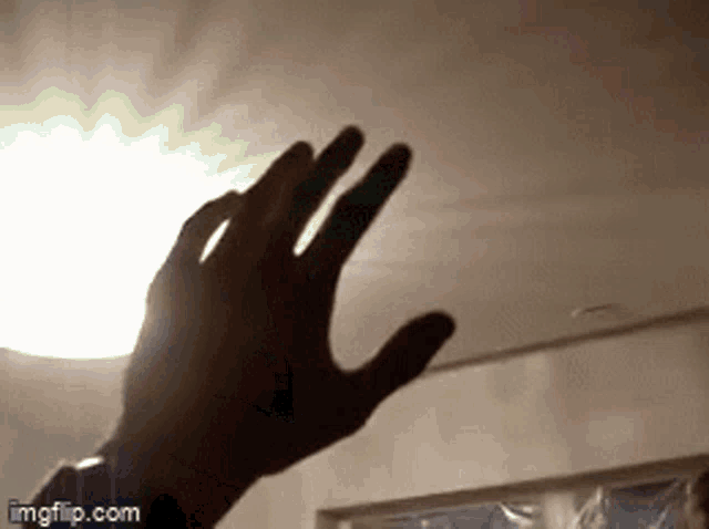a close up of a person 's hand reaching up towards a light