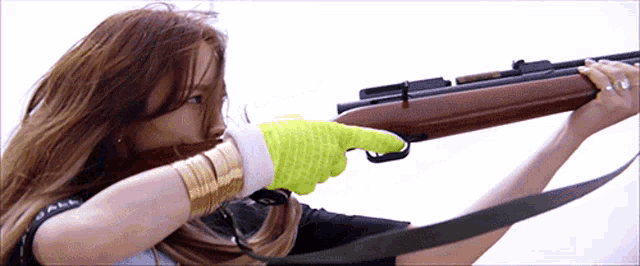 a woman in a yellow glove is pointing at a gun