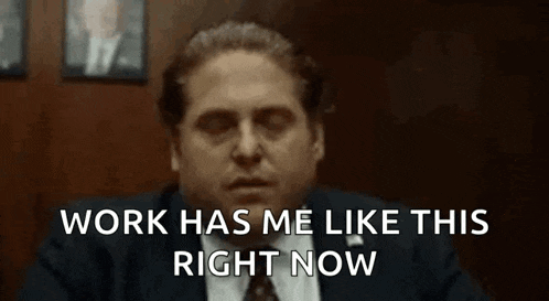 a man in a suit and tie is sitting at a desk and says `` work has me like this right now ''