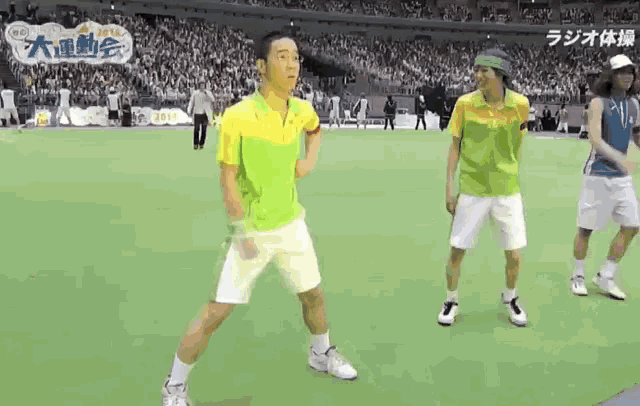 a man in a green shirt and white shorts stands on a tennis court