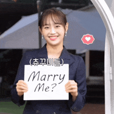 a woman in a suit holds a sign that says marry me