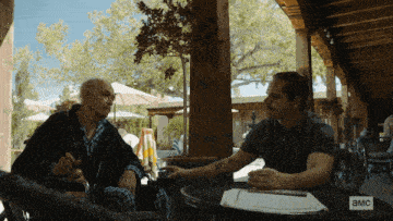 two men sit at a table with a sign that says ' a & m ' on it
