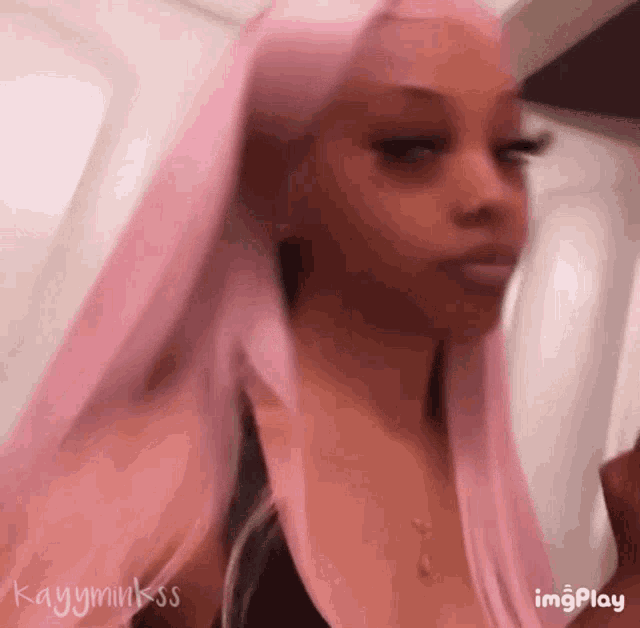 a woman with long pink hair is wearing a black tank top and a necklace .