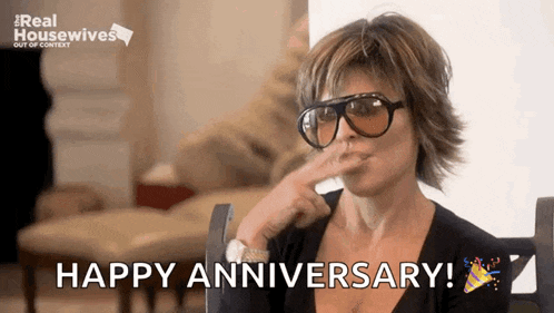 a woman wearing sunglasses is holding her hand to her mouth and saying happy anniversary .