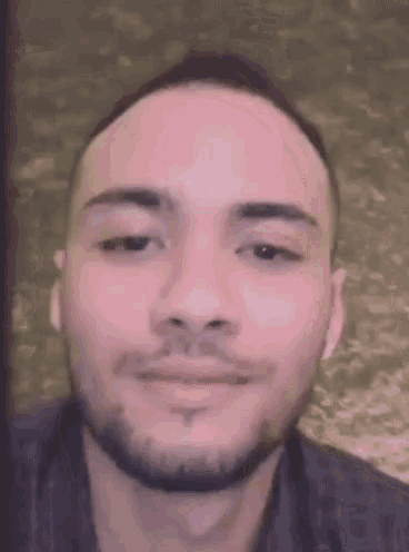 a close up of a man 's face with a beard looking at the camera .