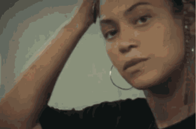 a close up of a woman wearing hoop earrings looking at herself in the mirror .
