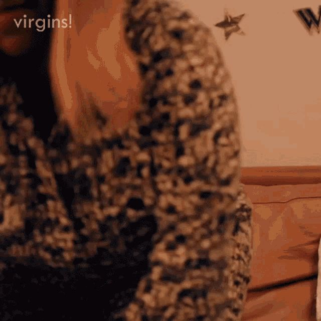 a woman in a floral shirt is sitting on a couch with the words virgins written above her