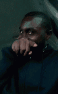 a man covering his mouth with his hand while wearing a black jacket