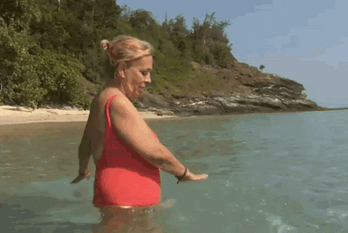 a woman in a red swimsuit is standing in the water .