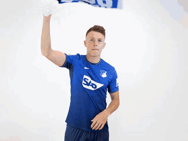 a man in a blue shirt holds up a scarf that says sap