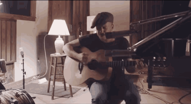 a man playing a guitar in front of a microphone in a dark room