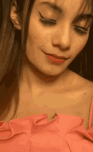 a close up of a woman 's face wearing a pink top .