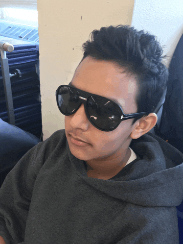 a boy wearing sunglasses and a grey hoodie