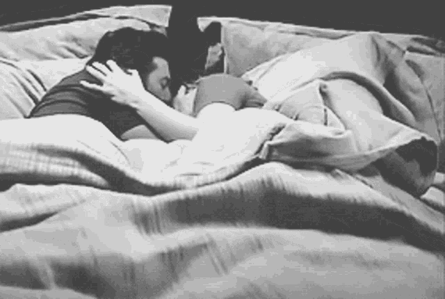 a black and white photo of a man and woman laying in bed