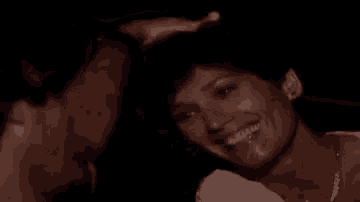 a close up of a woman smiling with a man behind her .
