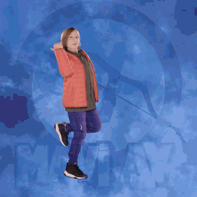 a boy in an orange jacket is flying through the air in front of a blue background with the letter m on it