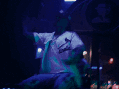 a man wearing a white shirt that says dinals on it is singing into a microphone
