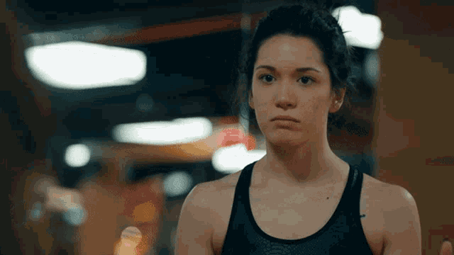 a woman in a black tank top has a tattoo on her arm