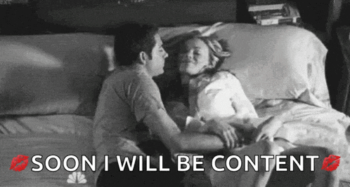a black and white photo of a man kissing a woman on a bed .