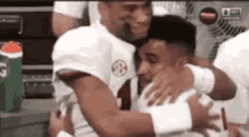 two football players are hugging each other in a locker room after a game .