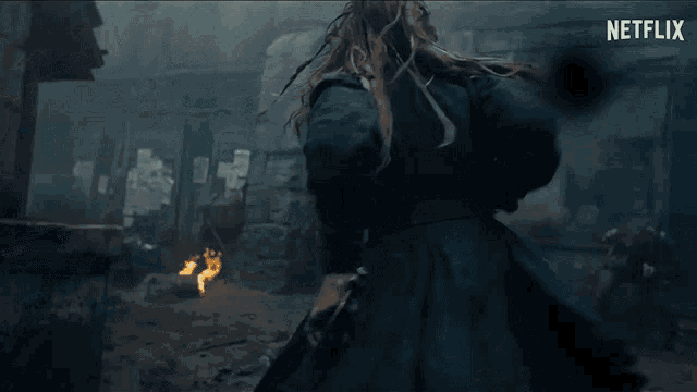 a woman in a blue coat is running with a sword in her hand in a netflix trailer .