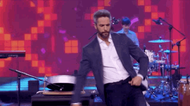 a man in a suit is dancing on a stage with a band behind him .