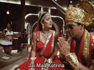 a woman in a red dress is sitting next to a man wearing a crown and the words jai maa katrina are above her