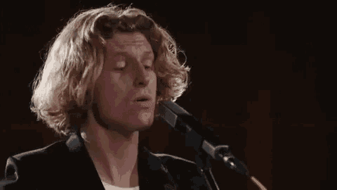 a man is singing into a microphone with his eyes closed
