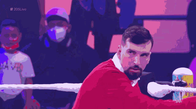 a man in a red shirt is in a boxing ring with the hashtag # 206live in the corner