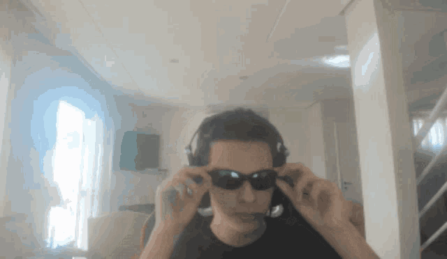 a man wearing headphones and sunglasses is sitting in a room
