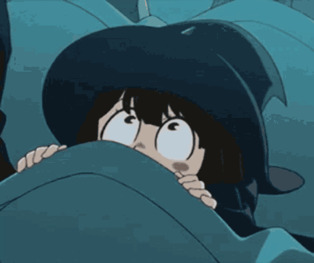 a girl in a witch hat is hiding behind a blanket