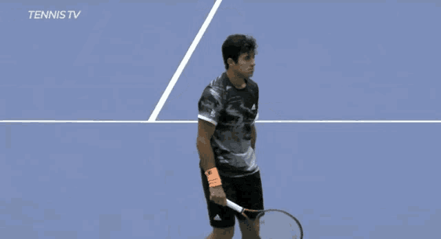 a man wearing a black adidas shirt is playing tennis
