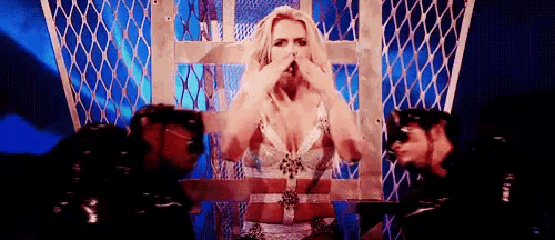a woman is sitting in a cage with two men behind her .