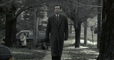 a man in a suit and tie walks down a sidewalk in front of a street sign that says charleston street