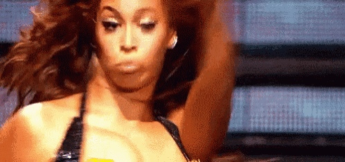 a woman in a bikini is dancing on a stage with her hair blowing in the wind .