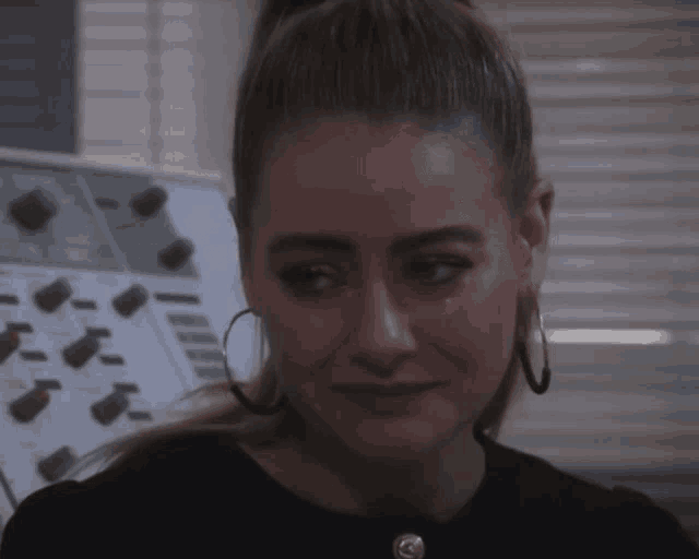a woman with hoop earrings is crying with a tear coming out of her eye