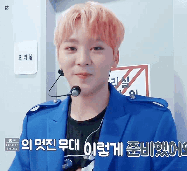a man wearing a blue jacket and a microphone with korean writing on it
