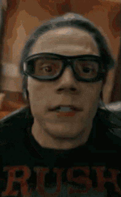 a close up of a man wearing glasses and a rush shirt