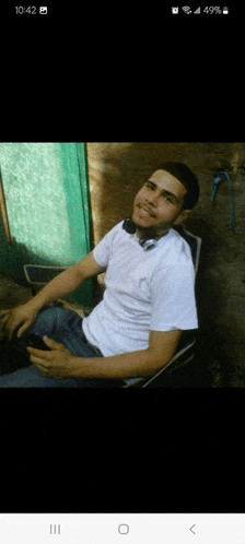 a man in a white shirt is sitting in a chair and smiling at the camera