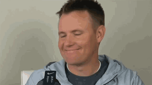 a man wearing a nike sweatshirt is smiling
