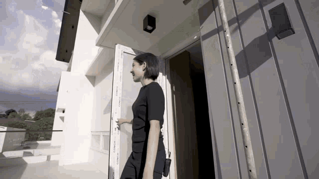 a woman in a black top is walking into a white building