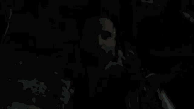 a man with a beard is standing in the dark holding a woman 's hand .