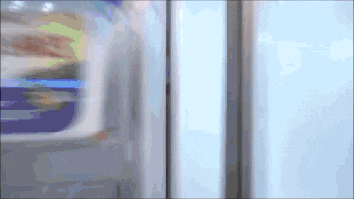 a blurred image of a refrigerator door with a blue bottle in the background